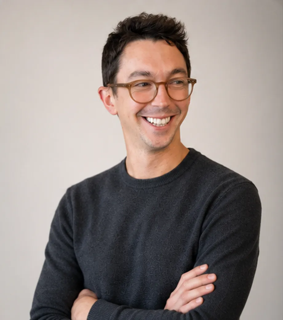 Adam Roberts, smiling, arms folded, wearing glasses and a dark jumper