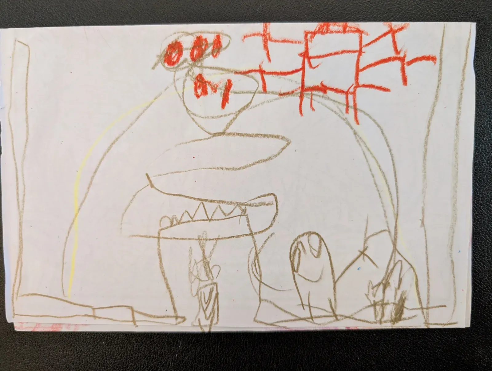 A crayon drawing by Adam's son of a big monster with sharp teeth and red eyes.
